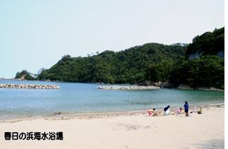 砂浜で家族が海水浴を楽しんでいる春日の浜海水浴場の写真
