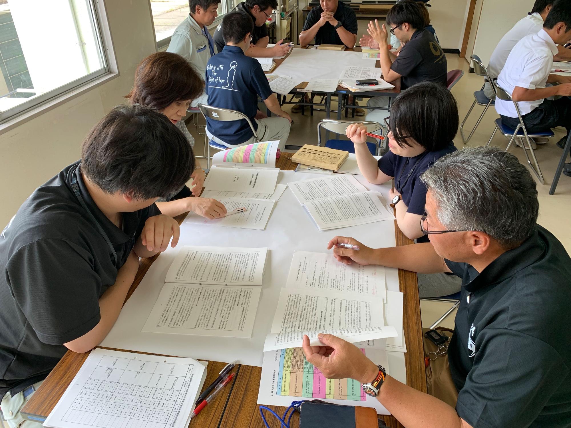 4人のグループで資料を見ながら話し合いをしている職員たちの写真