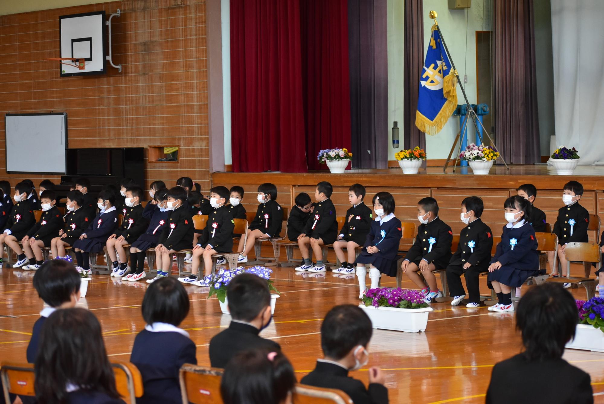 体育館で新入生の児童たちが座って入学式に参加している写真