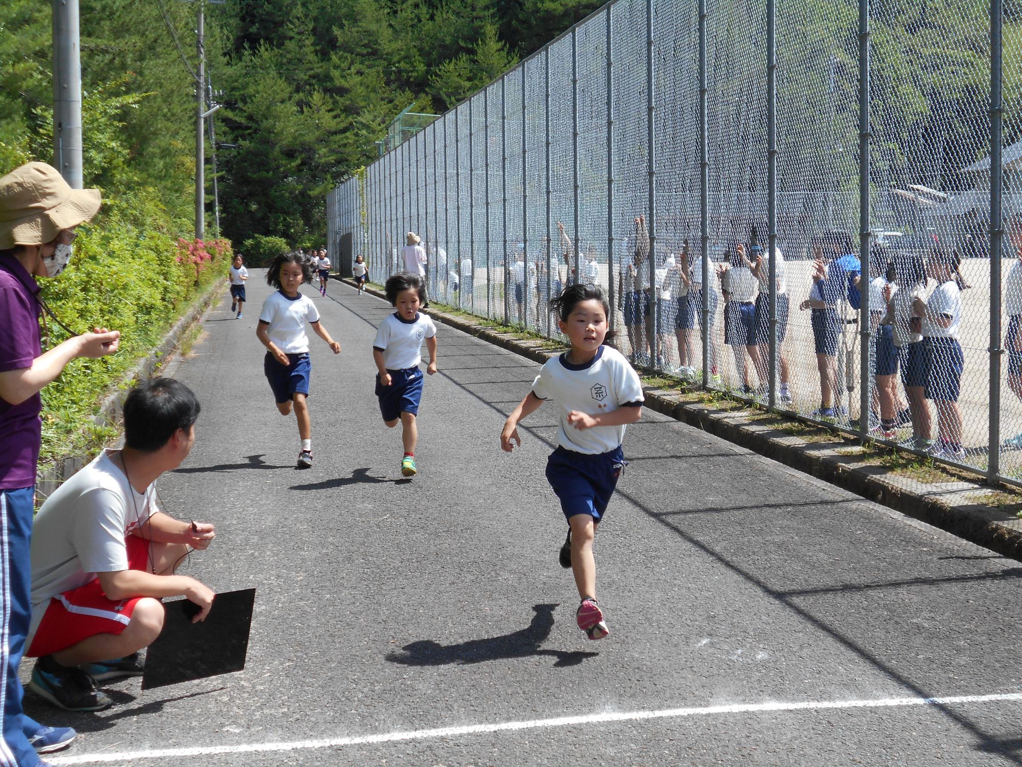 白いゴールラインを目指して、懸命に腕を振りながら走ってくる体操着姿の児童たちの写真
