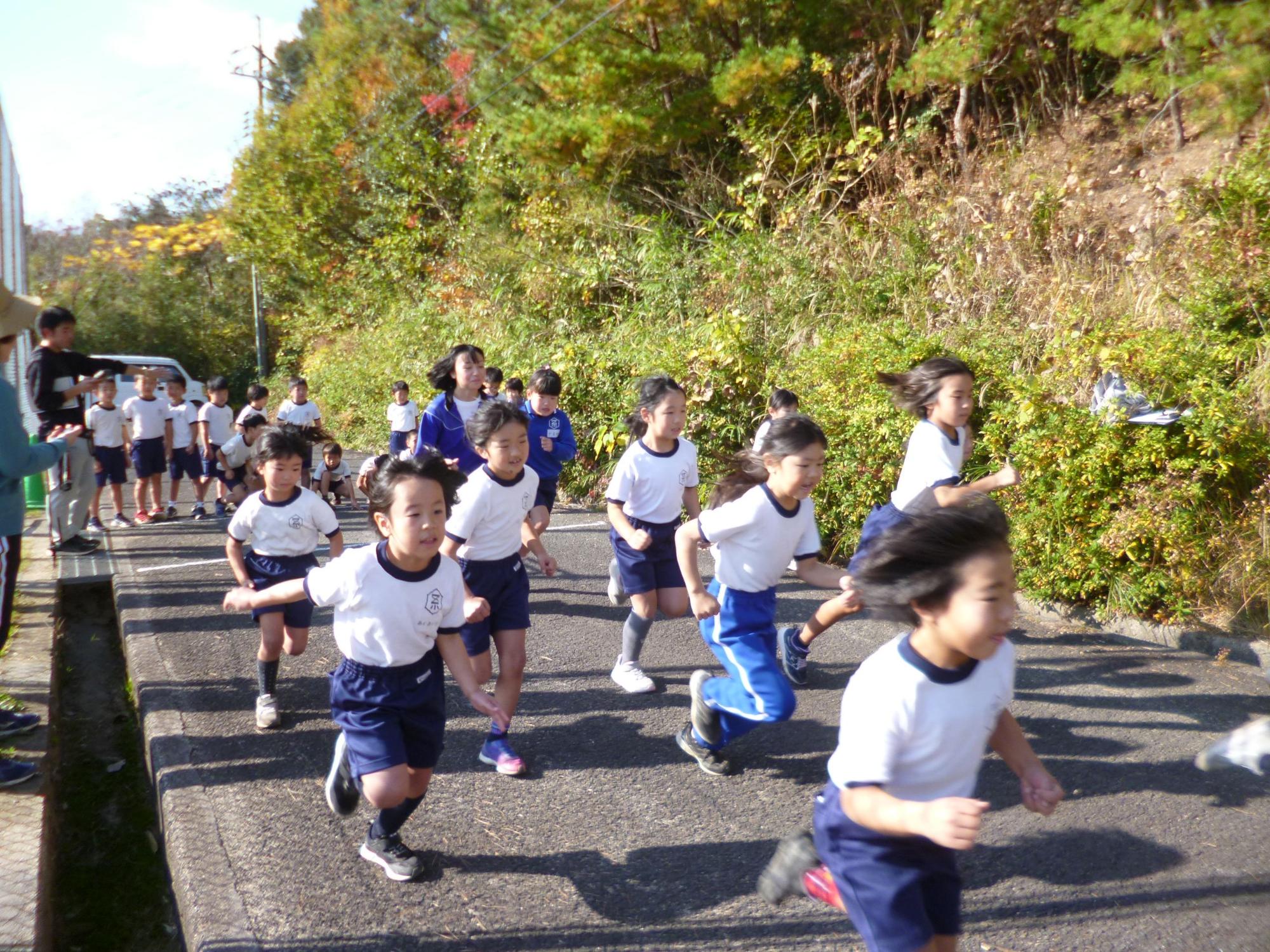沢山の体操着姿の児童たちが一斉に走り出している様子の写真