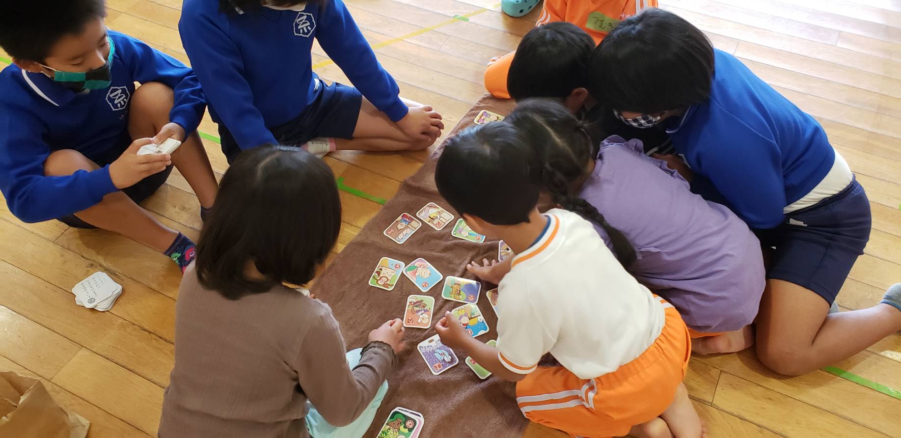 児童と園児が教室に座り、カードゲームを楽しんでいる様子の写真