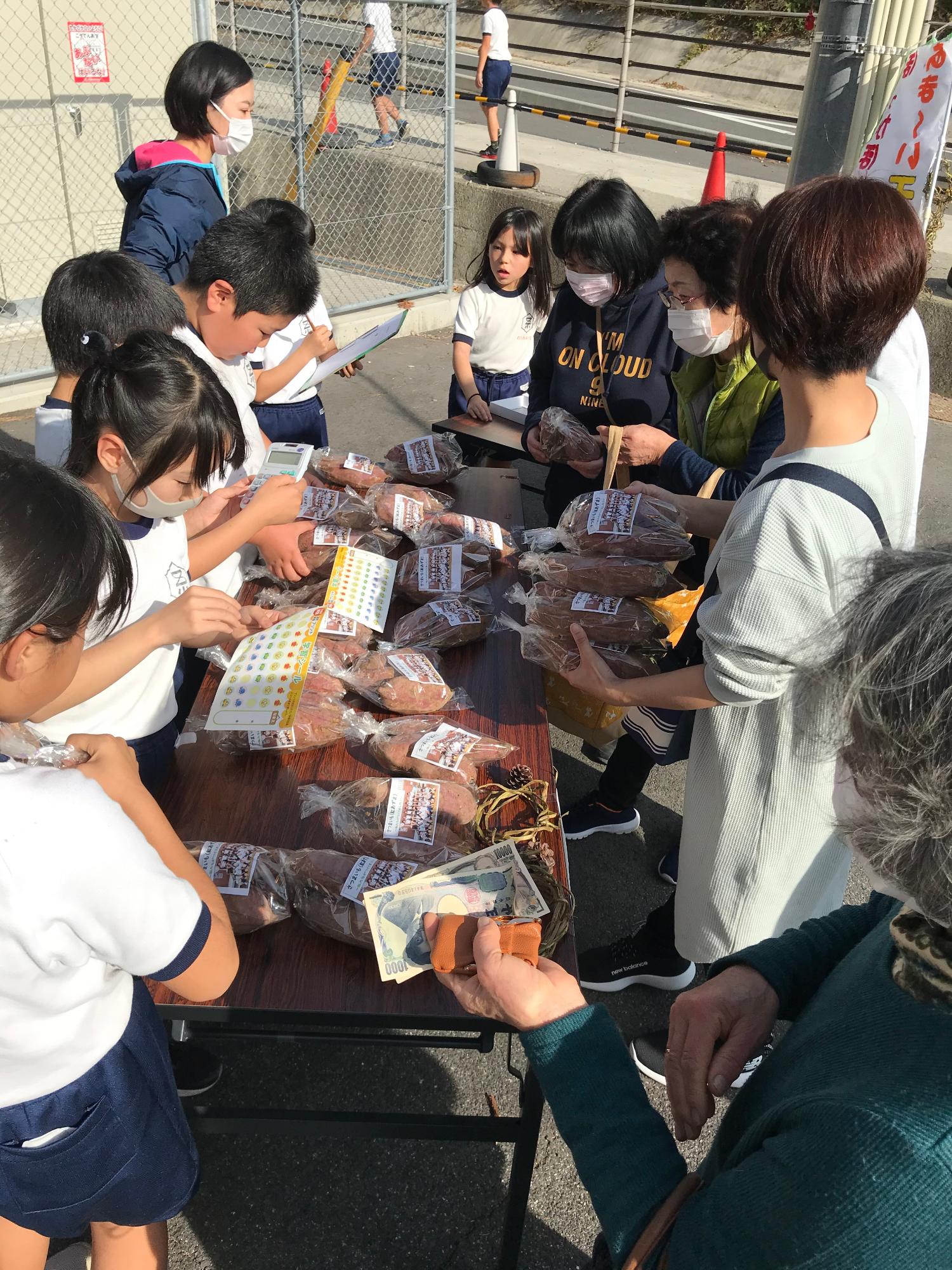 長机にさつまいもを陳列して、買いに来るお客さんの対応を一生懸命こなしている児童たちの写真