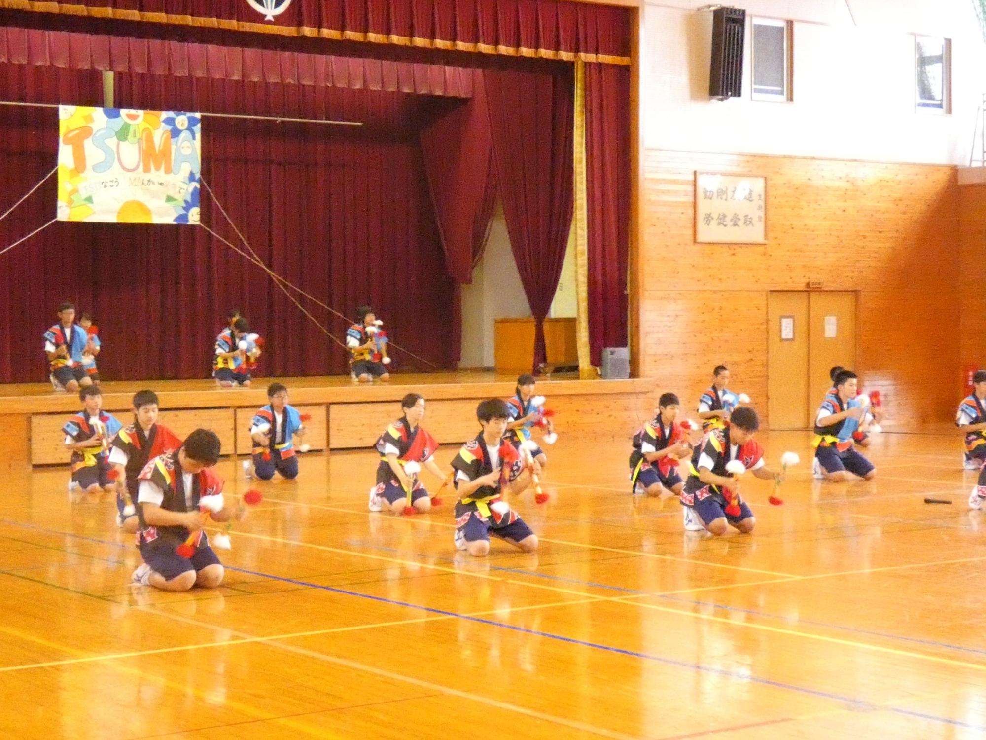 体育館で法被を着た生徒たちが演舞を披露している写真