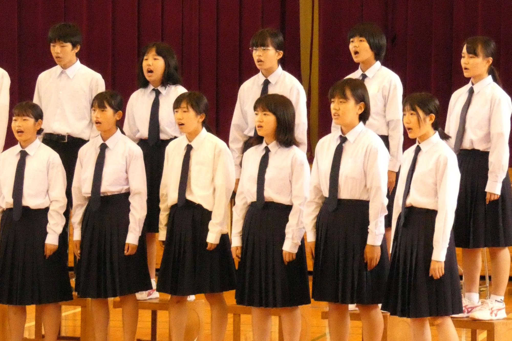 体育館で女子生徒たちが整列して合唱している写真