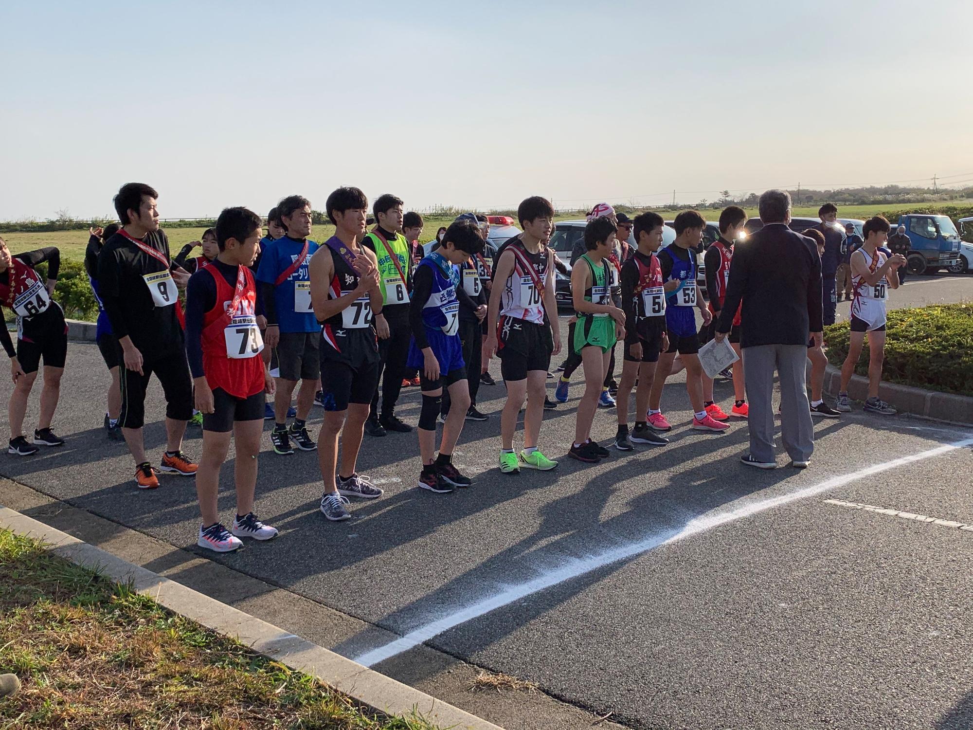 屋外で競走のスタートラインに立つ選手たちの写真