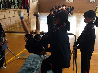 体育館で児童たちが鉄棒の練習をしている写真