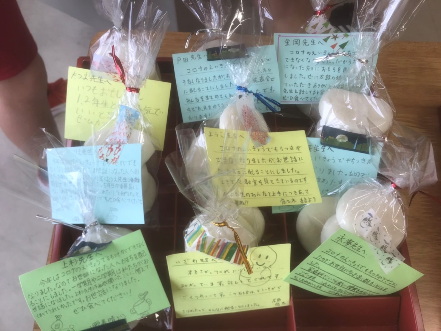先生への手紙が取り付けられ、ラッピングされたお餅が机の上に並べられている写真