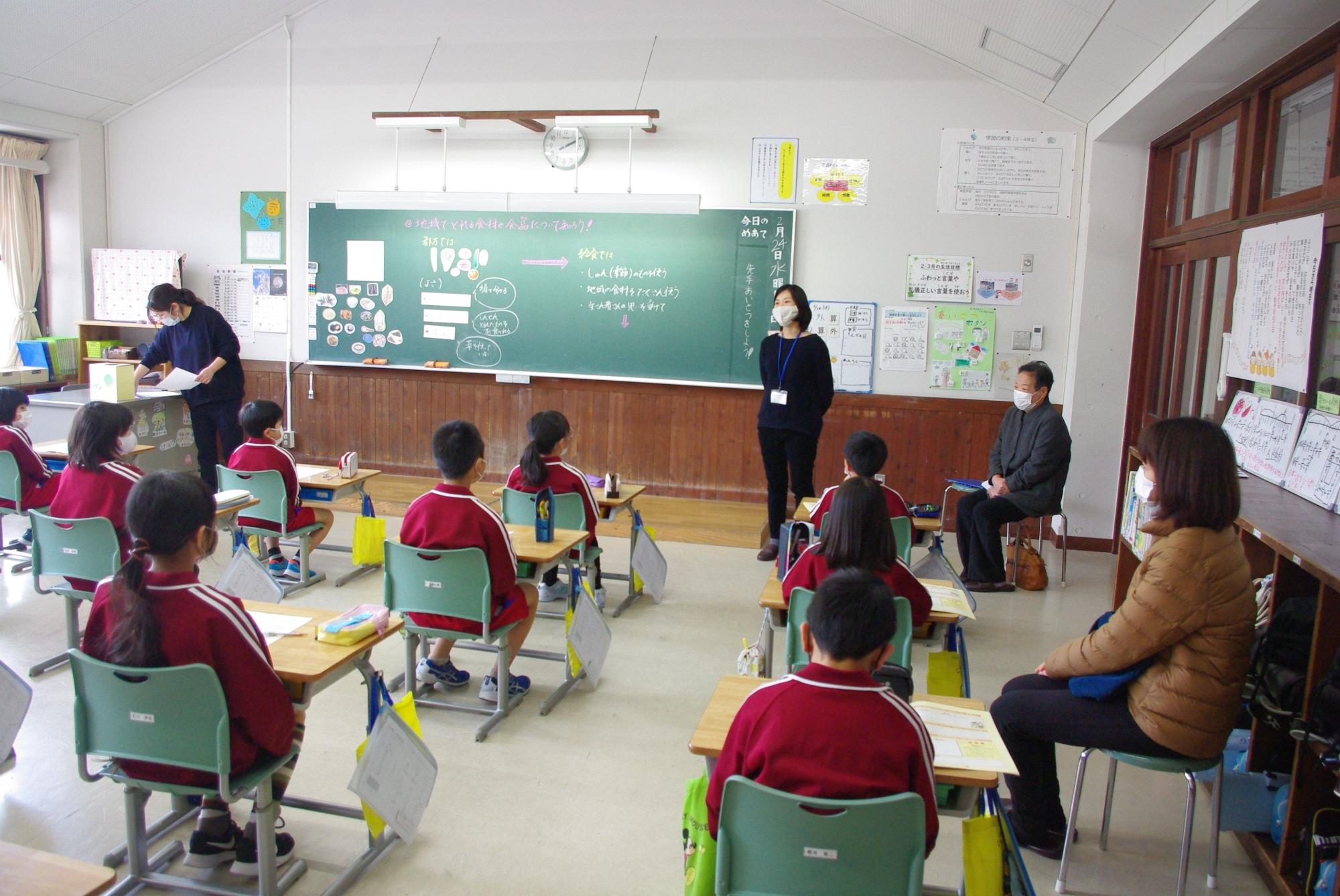 間隔をあけて席に座り先生の話を聞いている児童たちの写真