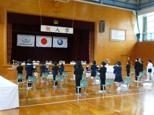 体育館で新入生が入学式に臨んでいる写真