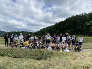 田植え体験を終えて田んぼの前で集合写真を撮っている写真