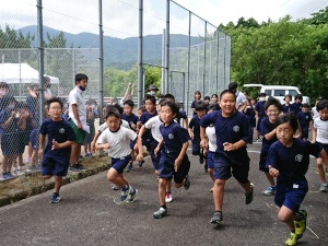 学校の外周コースを児童たちが勢いよく走り出している写真