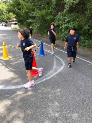 外でコースを回って児童たちが走っている写真