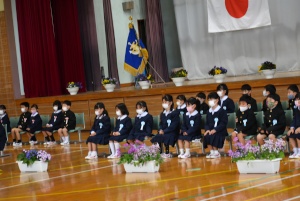 体育館で新入生が並んで座っている入学式の写真