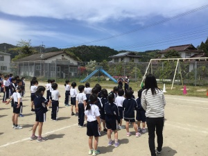 校庭で児童たちが整列して先生の話を聞いている写真