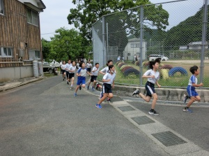 校庭の外周を並んで走る児童たちの写真