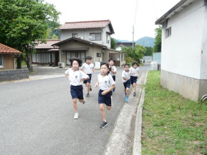 通学路を白い体操服で走る児童たちの写真