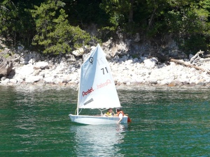 青い水面をヨットで進む児童たちの写真