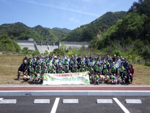 ダムを背景に全員で集合写真を撮る森林環境学習の写真