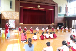 体育館で児童たちが円になって活動している写真