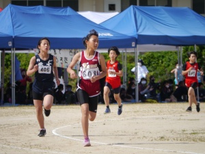 陸上大会で児童たちがトラックを走っている写真