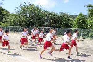 校庭で児童たちが一斉に走っている写真