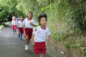 木陰の道を児童たちが走っている写真