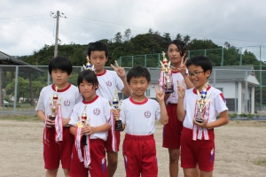 児童たちがトロフィーを手に記念撮影している写真
