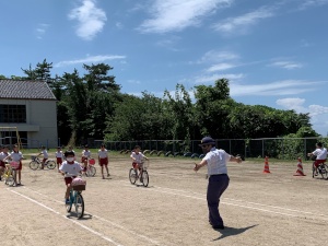 校庭で警察官の指導のもと、自転車交通安全教室を行っている写真