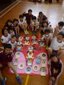 体育館で児童たちが赤組のポスターを囲んで記念撮影している写真