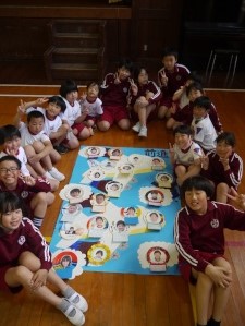 体育館で児童たちが青組のポスターを囲んで記念撮影している写真
