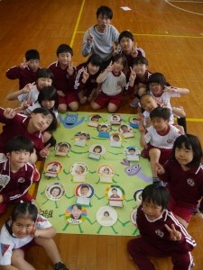 体育館で児童たちが緑組のポスターを囲んで記念撮影している写真