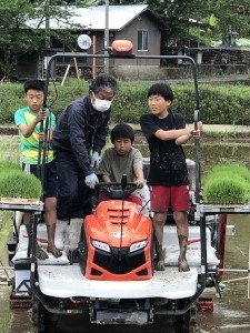 児童たちが田植え機に乗って作業している写真