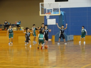 体育館で児童がバスケットボールをしている写真