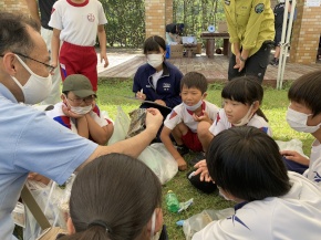 屋外で講師の話を聞く児童たちの写真
