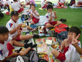 公園で児童が弁当を食べる写真