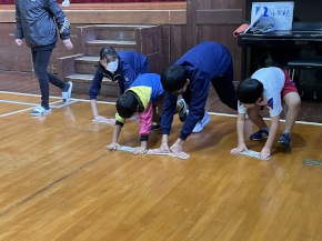 体育館で児童が雑巾がけ競争をする写真