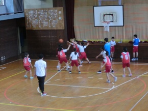 体育館で児童がバスケットボールをする写真