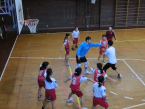 体育館で児童と先生が一緒にバスケットボールをする写真