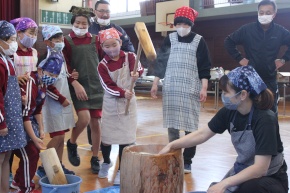 体育館で児童がもちつきを体験する写真