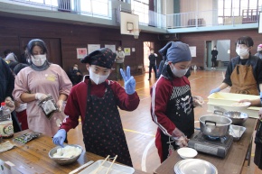 体育館で児童が調理体験をする写真