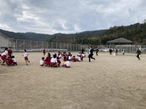 運動場で児童たちが集まり活動する写真