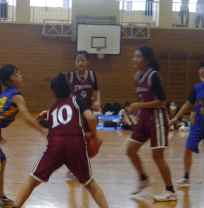 体育館で女子児童がバスケットボールをする写真