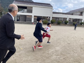 運動場で児童と先生が競走する写真