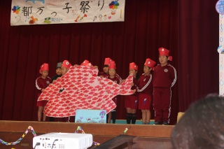 体育館の舞台で児童が大きな魚の劇をする写真