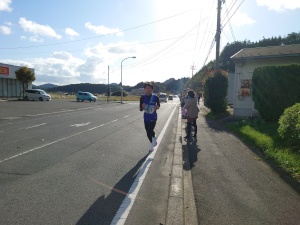 道路沿いで男子生徒がマラソン大会に参加している様子の写真