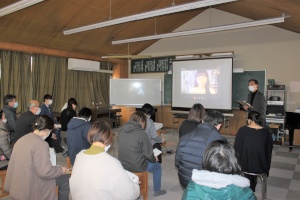視聴覚室でスクリーンを見ながら説明を受ける保護者たちの写真
