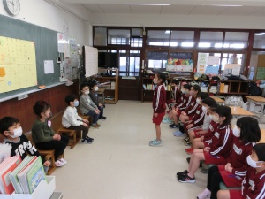 教室で低学年と高学年の児童が向かい合って発表をしている写真