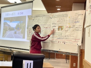 教室で大きな模造紙を使って発表をする児童の写真