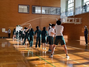 体育館で一列に並んで大縄跳びをする生徒たちの写真